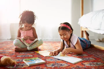 Two little girls reading on the floor